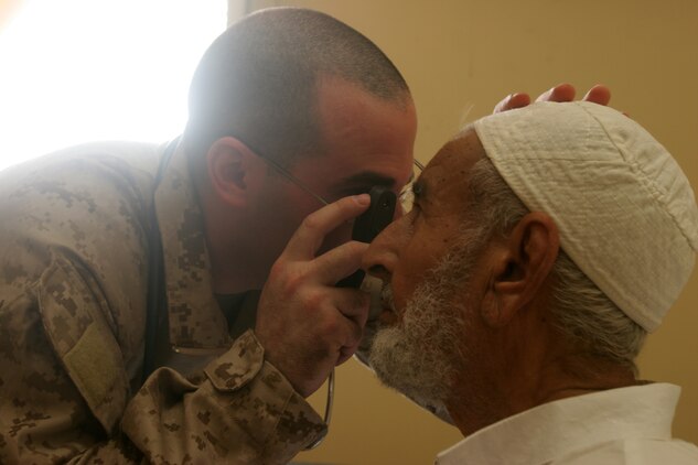 TRAILER TOWN, Iraq (July 31, 2008) – Lt. Cmdr. Lewis J. Fermaglich, medical officer for 2nd Low Altitude Air Defense Battalion, 1st Marine Logistics Group, looks into the eye of an elderly Iraqi man during a cooperative medical engagement at Trailer Town, July 31. The purpose of the CME was to increase the quality of life for residents here and to further develop and improve relationships with the locals. “We want to help the people help themselves and prevent disease,” said Fermaglich, from Evanston, Ill. Chest pain, abdominal pain, headache and sore throat were some of the most common complaints at the engagement. Iraqi Police, along with Marines with Bravo Battery, 2nd LAAD Bn., provided security for the mission.  Sixty-five Iraqis were seen during the visit, 55 percent of those patients were pediatric, 35 percent were adult males and 10 percent were adult females. This engagement was a continuation of a CME in Kabani which helped more than 130 Iraqis. In all, approximately 200 Iraqis were treated. (Photo by Lance Cpl. Robert C. Medina)::r::::n::