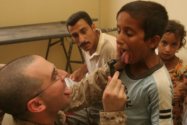 TRAILER TOWN, Iraq (July 31, 2008) - Lt. Cmdr. Lewis J. Fermaglich, medical officer for 2nd Low Altitude Air Defense Battalion, 1st Marine Logistics Group, examines the tonsils of an Iraqi child during a cooperative medical engagement here, July 31. The purpose of the CME was to increase the quality of life for residents and to further develop and improve coalition forces’ relationships with the locals. Health care and medical supplies were distributed to the locals. Preventative care and medicines were a major part of the engagement. Chest pain, abdominal pain, headache and sore throat were some of the most common complaints. Iraqi Police, along with Marines from Bravo Battery, 2nd LAAD Bn., provided security for the mission. (Photo by Lance Cpl. Robert C. Medina)