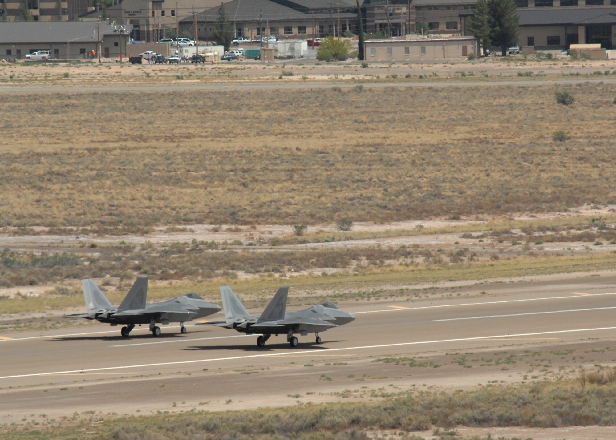 Col. Jeff Harrigian, 49th Fighter Wing commander, and Lt. Col. Mike Hernandez, 7th Fighter Squadron commander, taxi a pair of F-22A Raptors at Holloman Air Force Base, N.M., June 2. The jets are the first two Holloman-tailed F-22s to arrive on base. Prior to landing, the jets flew over the Tularosa Basin, allowing the local community a chance to witness the future of Holloman. (U.S. Air Force photo/Senior Airman Tiffany Trojca)