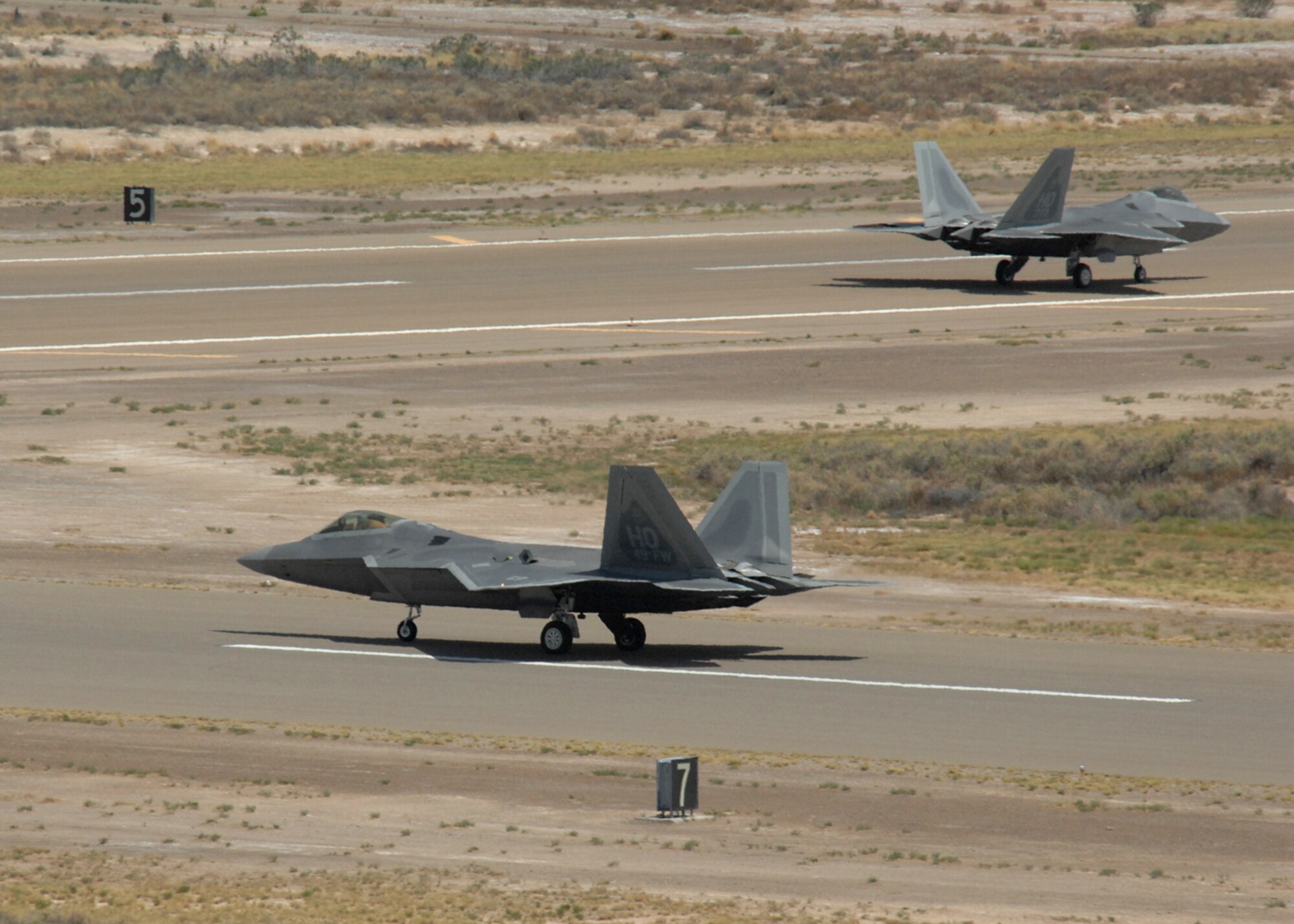 Col. Jeff Harrigian, 49th Fighter Wing commander, and Lt. Col. Mike Hernandez, 7th Fighter Squadron commander, taxi a pair of F-22A Raptors at Holloman Air Force Base, N.M., June 2. The jets are the first two Holloman-tailed F-22s to arrive on base. Prior to landing, the jets flew over the Tularosa Basin, allowing the local community a chance to witness the future of Holloman. (U.S. Air Force photo/Senior Airman Tiffany Trojca)