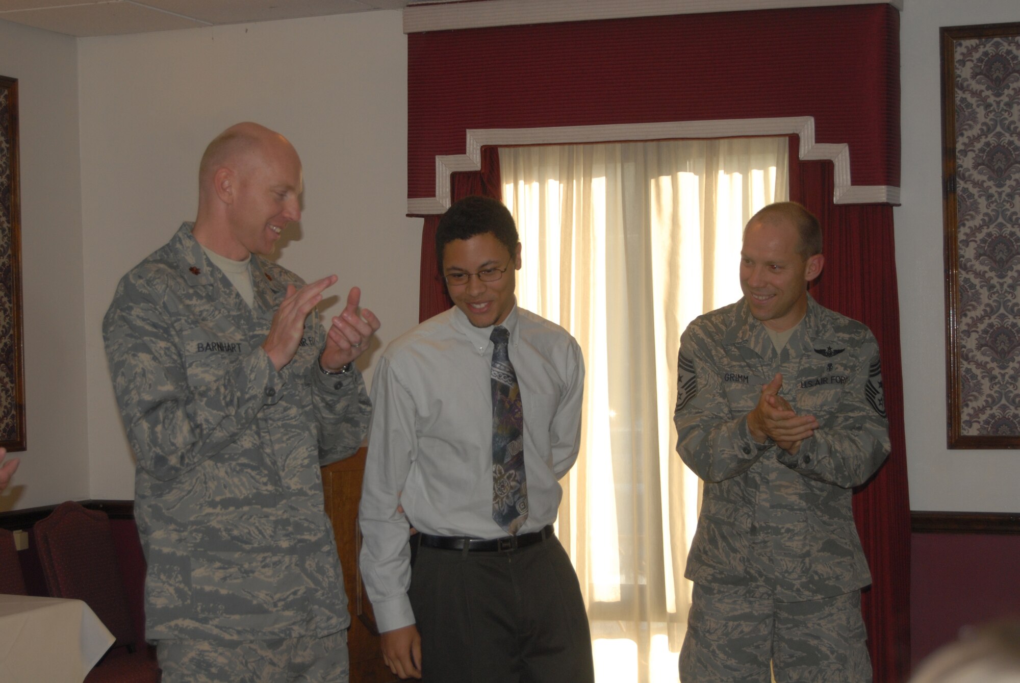 Maj. Brad Barnhart, Commander of Pope’s 43rd Communications Squadron, and 43rd Airlift Wing Command Chief Master Sgt. Michael Grimm applaud after presenting Lionel Earl III with a $2,000 scholarship from the North Carolina chapter of the Armed Forces Communication and Electronics Association, of which Major Barnhart is the acting president. Ten high school and college students, both civilian and military family members, from North Carolina received the scholarships from AFCEA, whose acting president in Major Barnhart. (U.S. Air Force Photo by Airman 1st Class Mindy Bloem)
