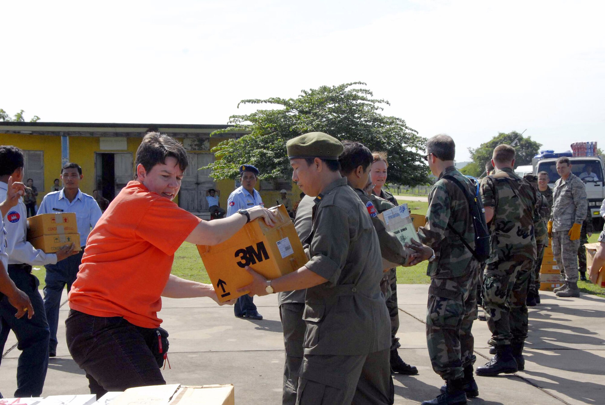 Master Sgt. Tracy Lewis (left) hands off a box of medical supplies to Cambodian Lt. Col. Mark Sophai May 24 at Kampong Chhnang Province Airfield, Cambodia. Multinational medical teams distributed the supplies to forward-operating locations for Operation Pacific Angel. The operation is a joint/combined humanitarian assistance operation in support of capacity-building efforts. Participating services include the active duty, Reserve and National Guard components of the Air Force, Army, Royal Thai air force, and Royal Cambodian armed forces.  Sergeant Lews is assigned to the from Pacific Air Forces International Heath Alliance, and Colonel Sophai is a doctor with the Royal Cambodian armed forces. (U.S. Air Force photo/Tech. Sgt. Tom Czerwinski)
