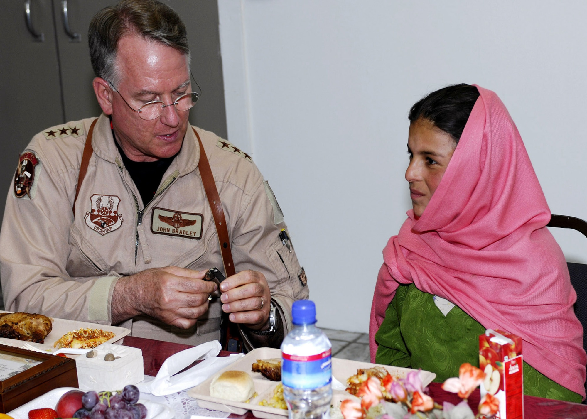 Lt. Gen. John Bradley unclasps a watch for Lamia, a 10-year-old Afghan girl he met last winter during a humanitarian aid drop to her village. Jan Bradley, wife of General Bradley, spearheaded a donation drive that collected several boxes of supplies specifically for Lamia and her village of Shakal and were presented here May 30. General Bradley is the Air Force Reserve Command commander. (U.S. Air Force photo/Capt. Toni Tones)