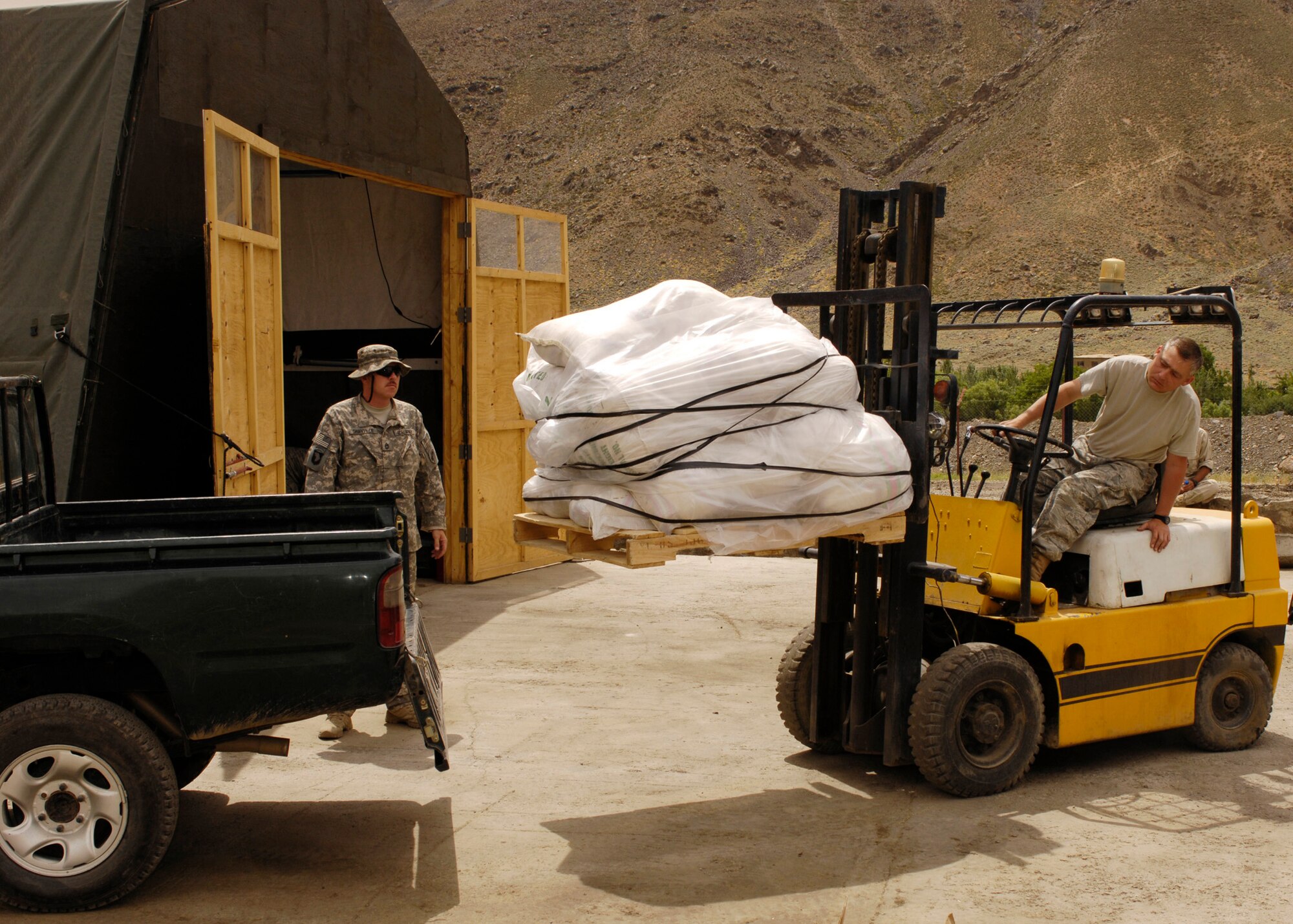 PANJSHIR PROVINCE, Afghanistan - Master Sgt. Timothy Godwin, Panjshir Provincial Reconstruction Team maintenance NCO-in-charge, loads rice onto a truck as Sergeant 1st Class Michael Granville spots him. The rice was delivered to 320 local Afghan families who live in the remote village of Dara. The PRT's primary mission is to rebuild Afghanistan and promote U.S. and Afghan relationships. Sergeant Godwin is deployed from the 2nd Logistic Readiness Squadron, Barksdale Air Force Base, La., and Sergeant Granville is deployed from the 451st Civil Affairs Battalion, Pasadena Texas. (U.S. Air Force photo by Master Sgt. Demetrius Lester)
