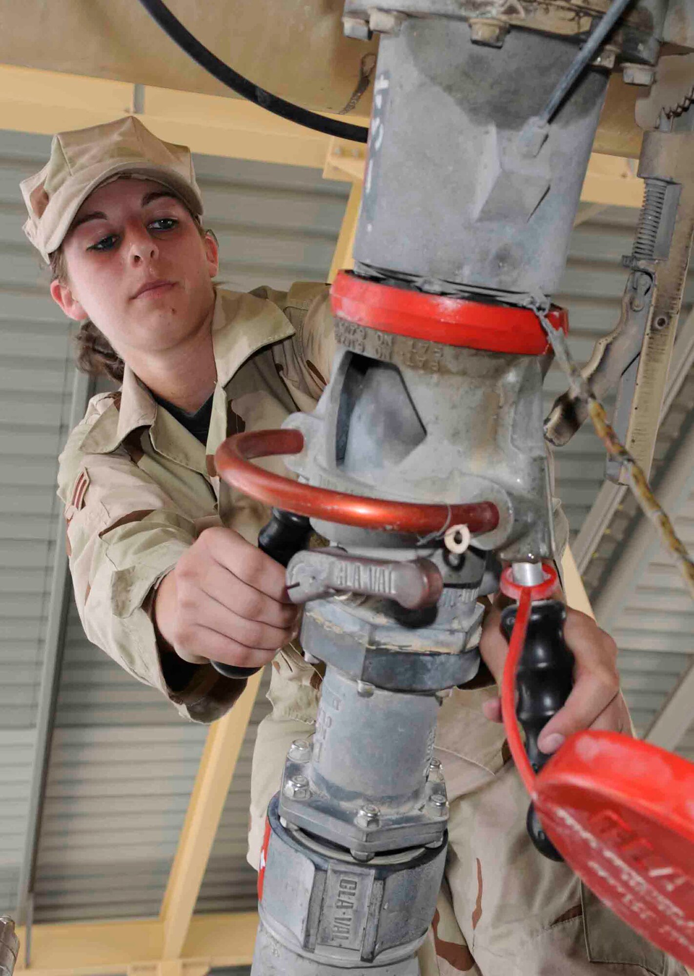 SOUTHWEST ASIA--Airman 1st Class Megan Cotton, 379th Expeditionary Logistics Readiness Squadron, hooks up a pantograph fueling system to the bottom loader of an R11 fuel truck at a Southwest Asia air base May 28. Airman Cotton, who is deployed from the 27th Special Operations Wing, Cannon AFB, N.M., uses the new system to fill 5,800 gallons of jet fuel in about 15 minutes. (U.S. Air Force photo/Tech. Sgt. Johnny Saldivar.)