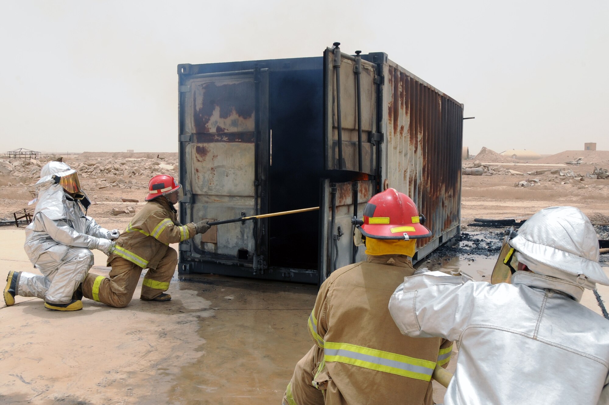 ALI BASE, Iraq -- Staff Sgt. Scott Herbert and Senior Airman Aaron Brackett, 407th Expeditionary Civil Engineer Squadron firefighters, instructs local Iraqi firefighters on the proper usage of the pike pole and advanced hand-line techniques while putting out a fire in a burning training container during a live fire exercise here June 2. The Air Force firefighters provide continuous training to local Iraqi firefighters, which equips them with basic firefighter skills to better serve their communities. Sergeant Herbert is deployed from Ellsworth AFB, S.D and Airman Brackett is deployed from Elmendorf AFB, Alaska. (U.S. Air Force photo/Tech. Sgt. Sabrina Johnson)