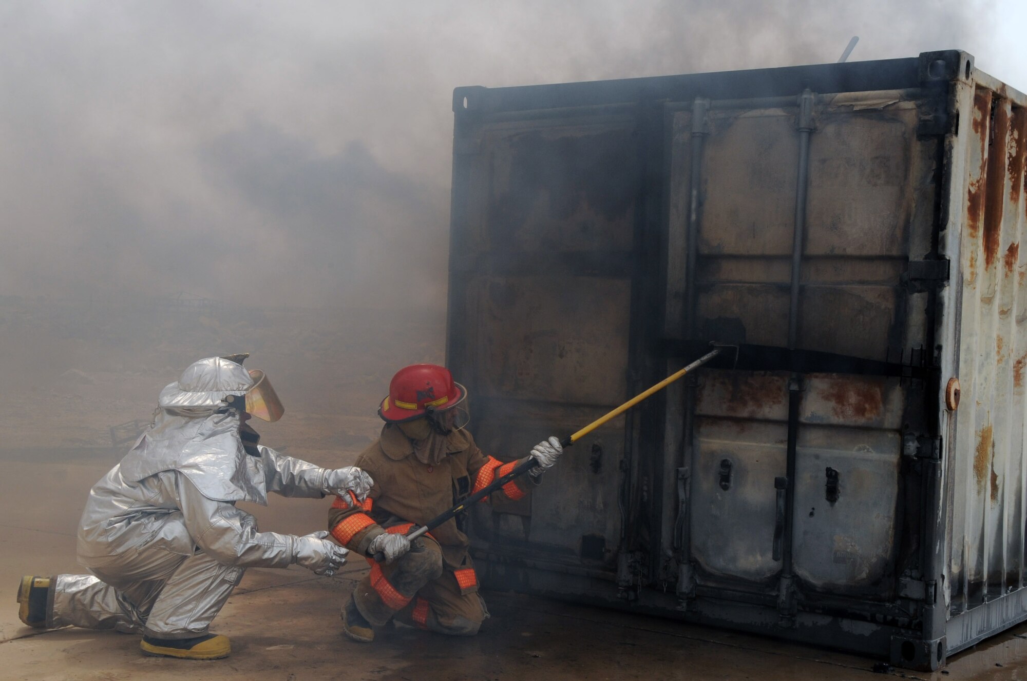 ALI BASE, Iraq -- Staff Sgt. Scott Herbert, firefighter, instructs an Iraqi firefighter on how to use a pike pole to open a door during a live fire exercise here June 2. The Air Force firefighters provide continuous training to local Iraqi firefighters, which equips them with basic firefighter skills to better serve their communities. Sergeant Herbert is deployed to the 407th Expeditionary Civil Engineer Squadron from Ellsworth AFB, S.D. (U.S. Air Force photo/Tech. Sgt. Sabrina Johnson)