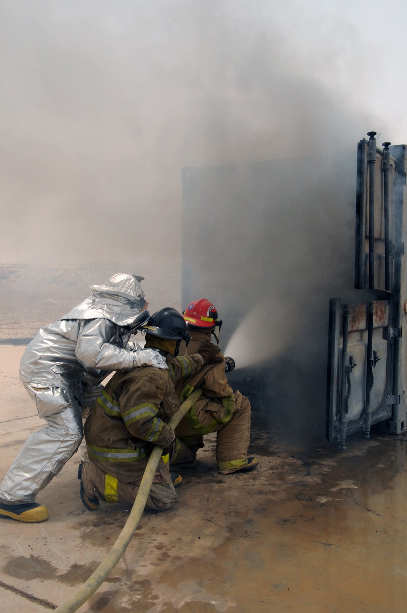 ALI BASE, Iraq -- Staff Sgt. Scott Herbert, firefighter, instructs local Iraqi firefighters on advanced hand-line techniques when putting out a fire in a burning training container during a live fire exercise here June 2. The Air Force firefighters provide continuous training to local Iraqi firefighters, which equips them with basic firefighter skills to better serve their communities. Sergeant Herbert is deployed to the 407th Expeditionary Civil Engineer Squadron from Ellsworth AFB, S.D. (U.S. Air Force photo/Tech. Sgt. Sabrina Johnson)
