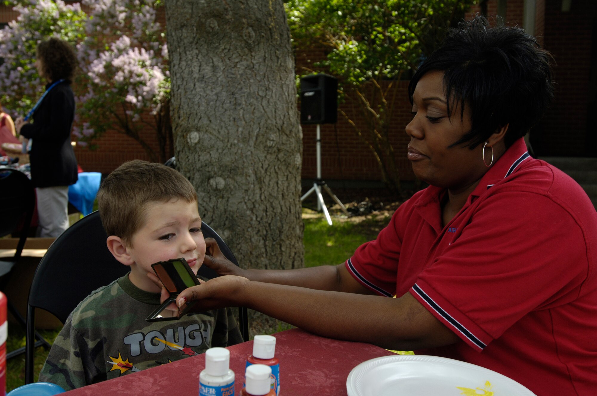 FAIRCHILD AIR FORCE BASE, Wash. – Javonika McCree helps C.J. Ward, son of 1st Lt. Clayton Ward, 92nd Air Refueling Squadron, with his face paint during the Spouse’s Appreciation Day cookout at the Airman & Family Readiness Center May 30. (U.S. Air Force photo / Senior Airman Eunique Stevens)