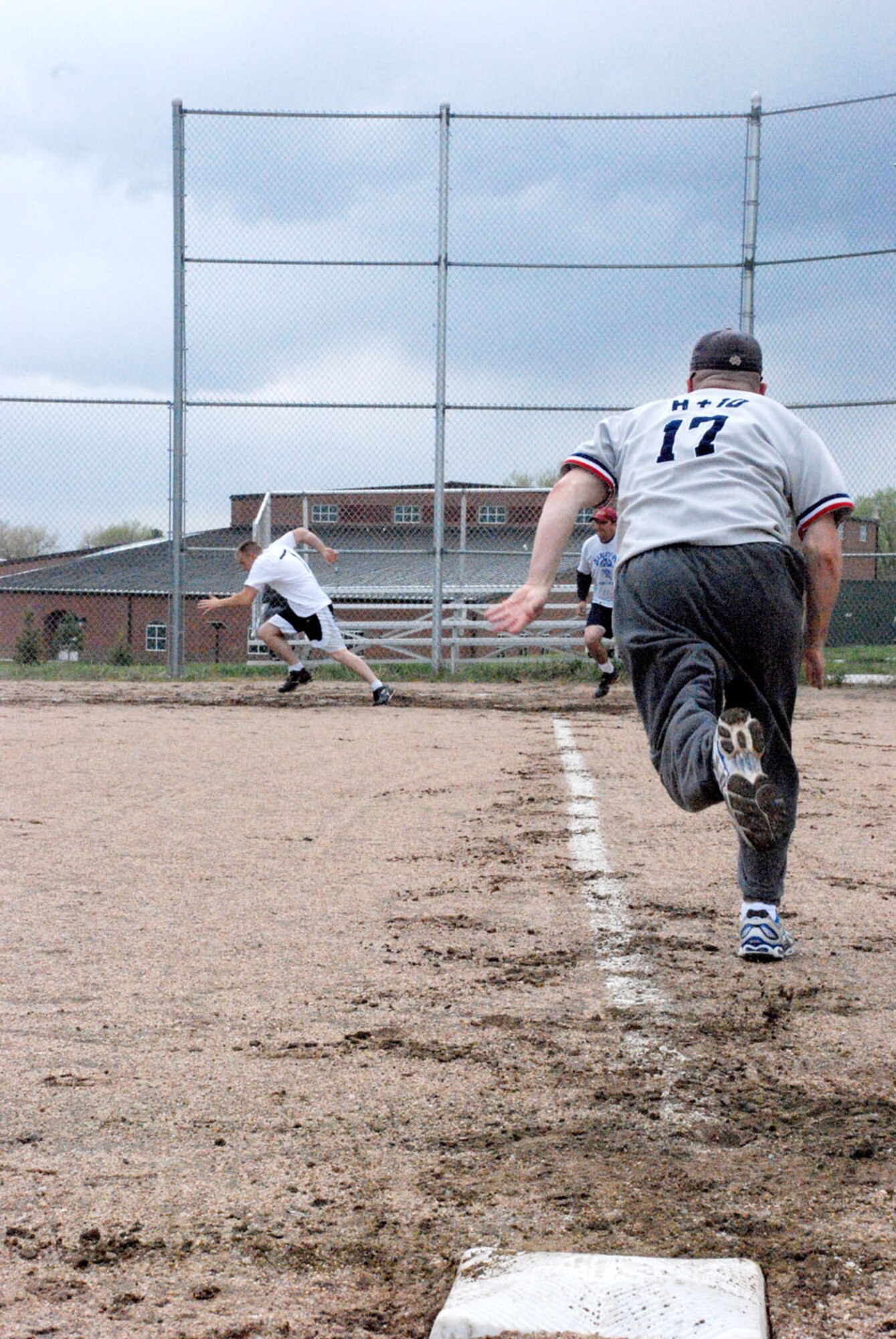 Tech. Sgt. Chris Huelsenbeck, 30th AS 153rd AW and 37th HS team, runs toward home base as a fellow team member hits the ball.