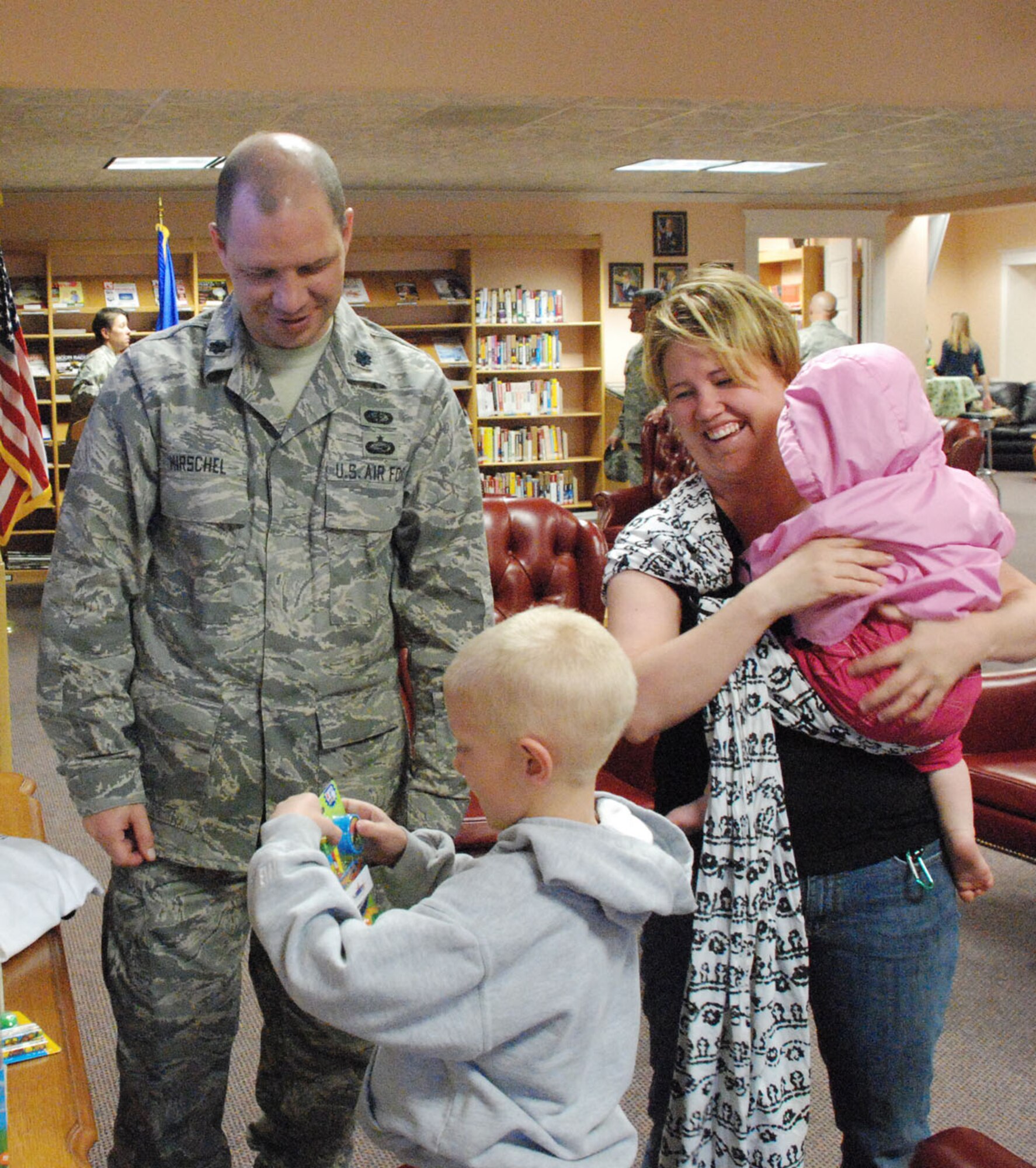 Lt. Col. Carleton “Chop” Hirschel, 90th Force Support Squadron commander, talks May 22 to Stephanie, Gianna and Max Schrader about the toys that are available at the communibrary.