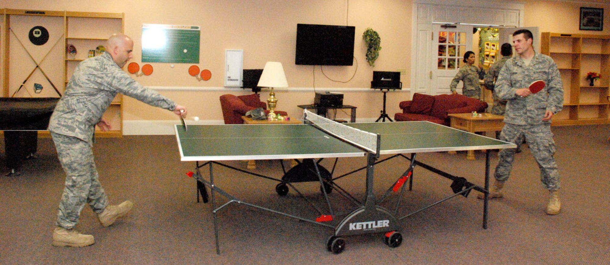 First Lt. Tommy Rutherford, 90th Mission Support Group, and 2nd. Lt. Zachary Bass, 90th Force Support Squadron, play a game of ping pong in the communibrary during its grand opening May 22. The communibrary combines both the library and the community center to form one facility that houses many needs. While accessible for months, the grand opening marked its official completion.