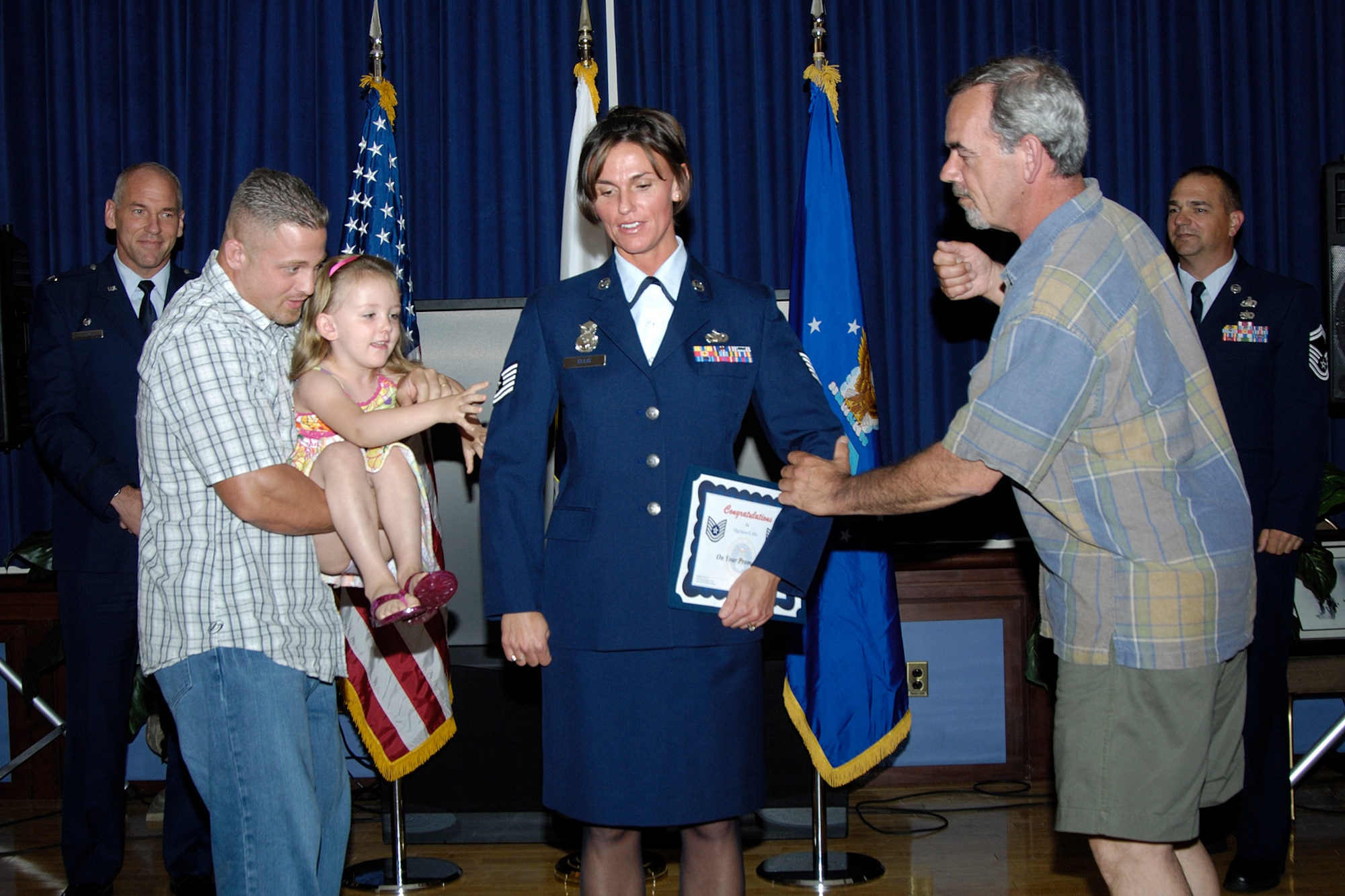 HANSCOM AFB, Mass. – Newly promoted Tech. Sgt. Susan Ellis, 66th Security Forces Squadron, gets her stripes tacked on by her husband Tommy Ianuzi and her daughter Rayne Ianuzi (left) and her father Ed Ellis (right) during the enlisted promotion ceremony May 30 at the Minuteman Club. (U.S. Air Force photo by Linda LaBonte Britt)