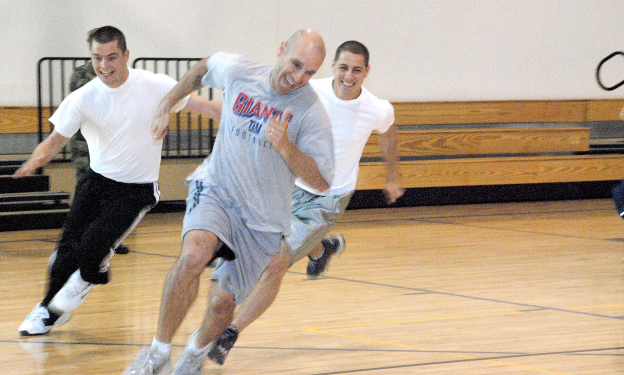 Airman 1st Class Norman Strand, 30th Airlift Squadron, Tech. Sgt. David Bedner, 90th Force Support Squadron, and Airman Basic Chad Hardesty, 90th FSS, race along the track inside Freedom Hall Fitness Center May 21 as part of May Fitness Month's Jeopardy contest. The contestants had to run around the track to find the correct answer, which was held by a gym staff member (Photos by 2nd Lt. Brooke Brzozowske).