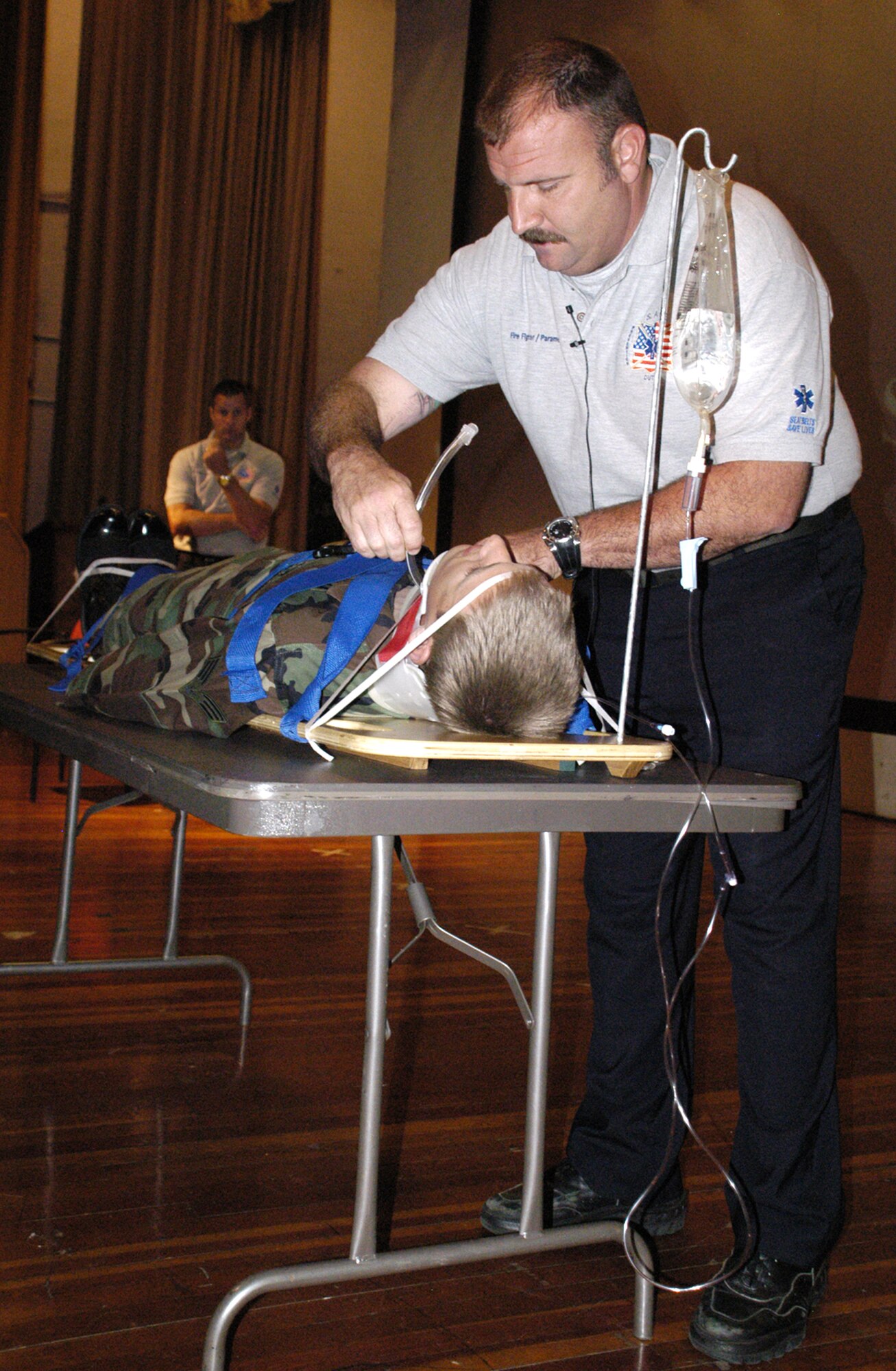 Pat Kelly, Orlando City Fire Department firefighter and paramedic, demonstrates making an incision in the throat to place a suction tube into the surgical opening to drain blood and fluid from Senior Airman Alex Keel, 736th Aircraft Maintenance Squadron, so he is able to breathe. Airman Keel modeled as a accident victim during the 101 Critical Days of Summer Briefing. (U.S. Air Force photo/Airman 1st Class Shen-Chia Chu)