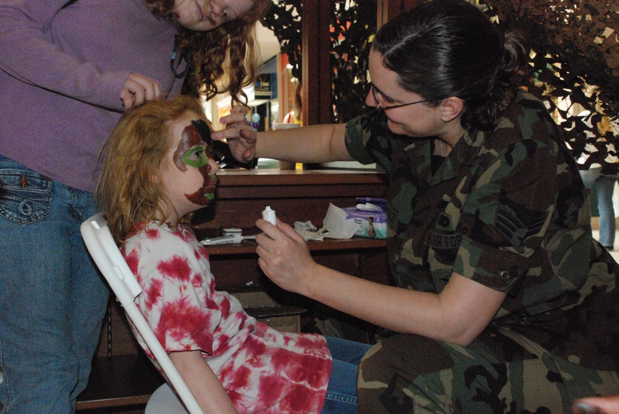 Senior Airman Kristina Buckholz, 90th Missile Security Forces Squadron, paints Haley Christoffersen's face with camouflage paint inside the mall. Many of Warren's helping agencies had booths set up to educate people and Airmen on the educational and medical benefits the military offers. There was also a Hall of Honor where people could sign a banner thanking deployed troops. The banner is scheduled to be sent overseas soon.