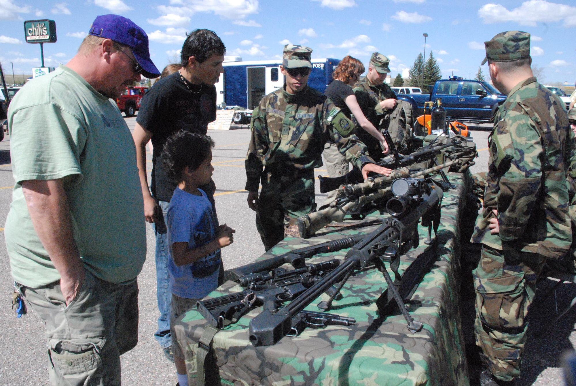 Members of the 90th Security Forces Group explain different weapons available for their use to a group of Armed Forces Day attendees. Armed Forces Day included numerous indoor and outdoor events ranging from face-painting to static helicopter displays.