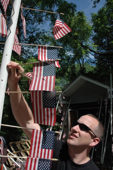 Staff Sgt. Paul Evans, from the U.S. Air Force Expeditionary Center, places an American flag in a pipe as part of a volunteer effort to repair a vandalized flag memorial in Cherry Hill, N.J., May 28, 2008.  The memorial, created by Cherry Hill resident Mr. Michael Bloom, has an American flag posted for every service member lost in Operation Iraqi Freedom.  (U.S. Air Force Photo/David Gard)