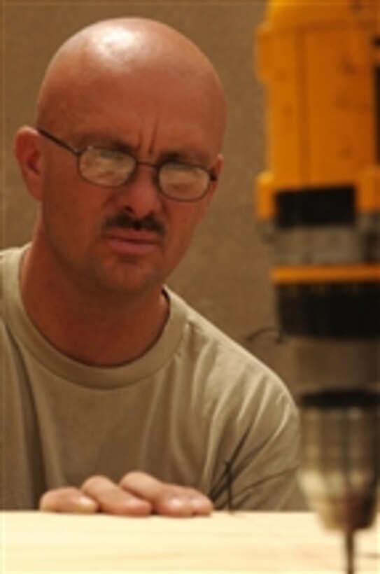 U.S. Army Sgt. Bob Crandall, a carpenter mason from the Minnesota National Guard's 851st Vertical Engineer Company, steadies a board as a fellow soldier drives a screw into it at Joint Security Station Sadr City in Baghdad, Iraq, on May 27, 2008.  Crandallís team is building desks for members of the 432nd Civil Affairs Battalion.  