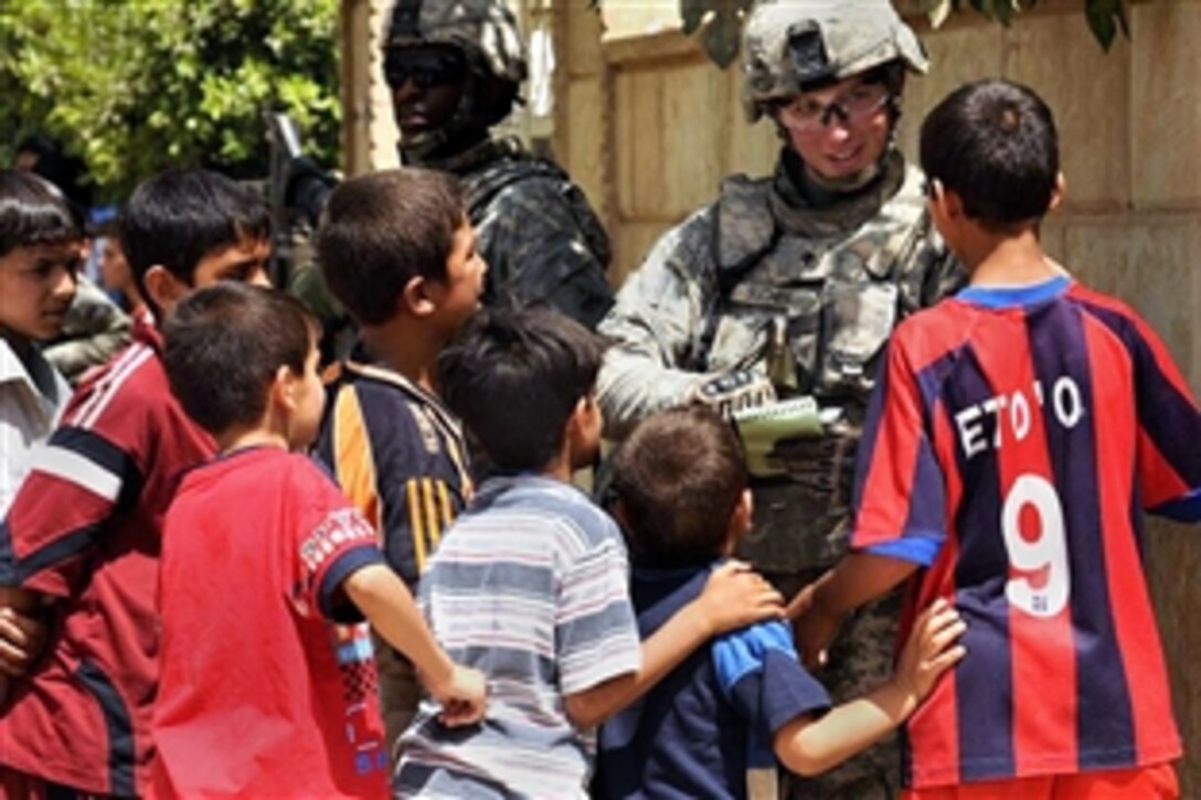 U.S. Army Spc. James Sucher is surrounded by Iraqi children who want to practice English outside a Sadr City school, Baghdad, May 30, 2008. Sucher is assigned to the 1st Battalion, 6th Infantry Regiment, Task Force Regular. More than 100 young Iraqi men showed up at the school to apply for an opportunity to join the neighborhood watch program. 