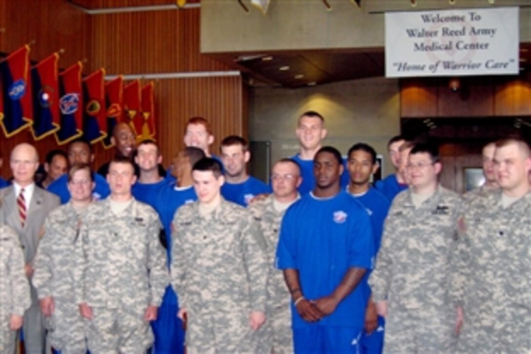 Army Secretary Pete Geren, left, poses for a photo with wounded warriors and the University of Kansas Jayhawks 2008 national champion men's basketball team, at Walter Reed Army Medical Center in Washington, June 2, 2008. The basketball players visited injured soldiers recovering at the medial center.