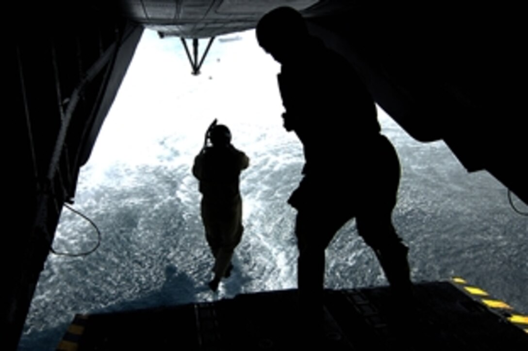 U.S. Navy Petty Officer 1st Class Adam Eddingfield, left, jumps off the back ramp of an MH-53 Pave Low helicopter assigned to Marine Heavy Helicopter Squadron 464 over the Gulf of Aden during a training mission, May 31, 2008. Eddingfield, a diver, is assigned to Combined Joint Task Force - Horn of Africa out of Camp Lemonier, Djibouti. 