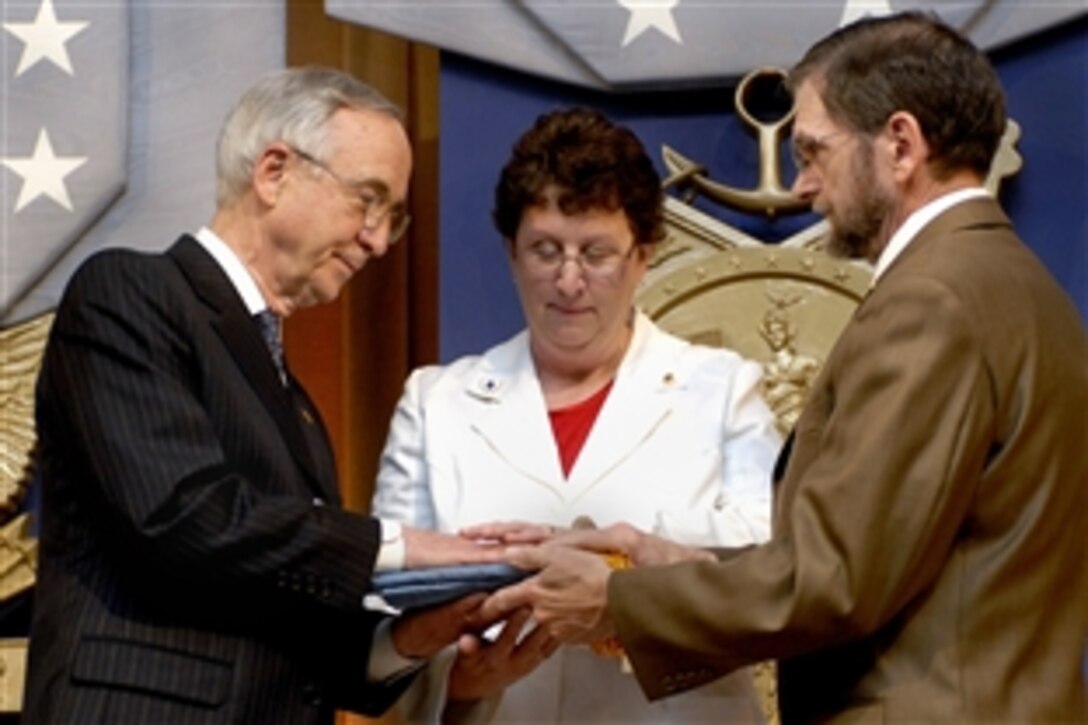 U.S. Deputy Defense Secretary Gordon England, left, presents the Medal of Honor flag to Tom and Romayne McGinnis, parents of Army Pfc. Ross A. McGinnis, during a ceremony in the Pentagon's Hall of Heroes, June 3, 2008. McGinnis was awarded the medal posthumously for his valor in battle in Iraq in an act that saved three lives. 