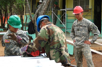 SOTO CANO AIR BASE, Honduras--United States Military Academy cadet Walter Arevalo observers U.S.soldier and a Honduran soldier working at a school renovation site in Honduras during his visit here as part of Academy?s Academic Individual Advanced Development, a program similar to summer internships in whichengineering cadets gain valuable, real-world experience. (U.S. Army photo by Cadet 2nd Class Ryan Kim)