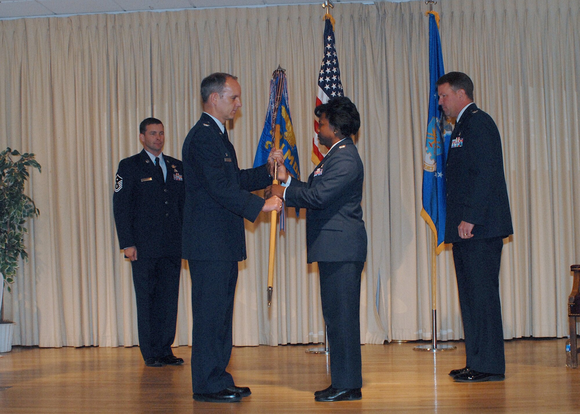 Col. Leslie Dixon accepts the 341st Medical Group guidon and command of the organization from Col. Michael Fortney, 341st Space Wing commander during a change of command ceremony May 29. Outgoing commander, Col. Bradley Herremans, right, looks on along with 341st MDG first sergeant Master Sgt. Michael Ammons. (U.S. Air Force photo/Christy Mason)