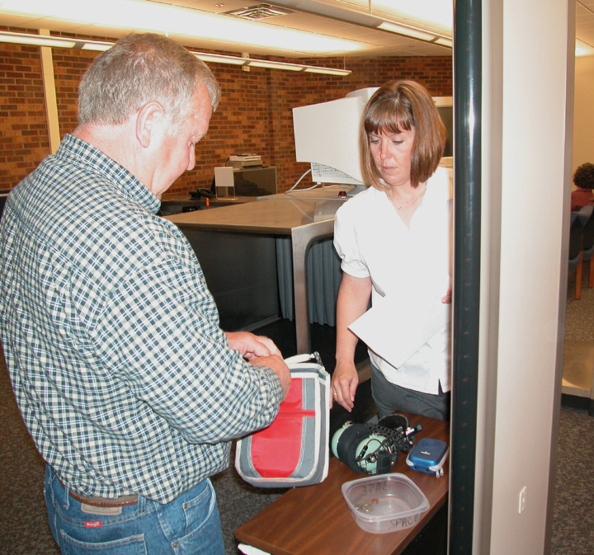 GRISSOM AIR RESERVE BASE, Ind., -- Harold Folden, a participant in a recent civic leader flight, has his baggage checked by Shaun Bullick, an air traffic control specialist manager.  Many of the same policies regarding carry-on items on commercial aircraft apply to military planes and require all passengers to be screened prior to boarding the aircraft. (Air Force photo/Senior Airman Ben Mota)