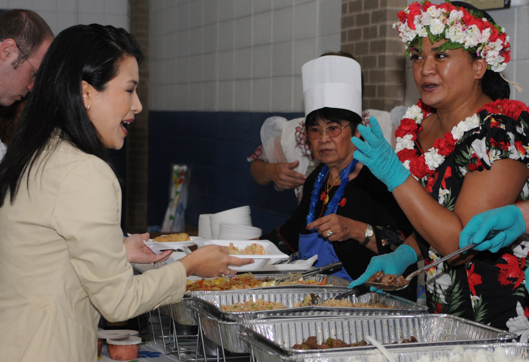 WLOX-TV education reporter Trang Pham-Bui, left, guest speaker for the event, samples the Asian cuisine offered by retiree Linda Fanungao and Angie Braden, 332nd TRS.  (U.S. Air Force photo by Kemberly Groue)