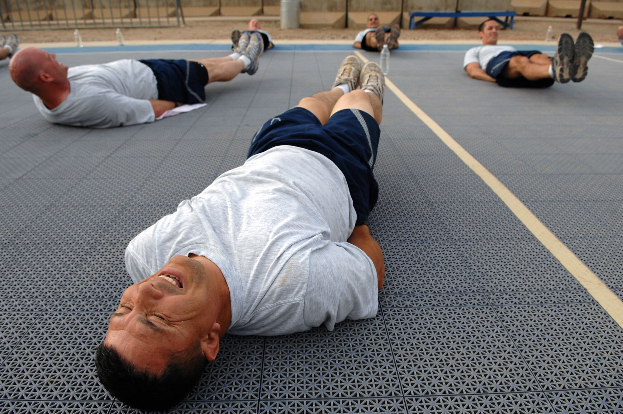 Tech. Sgt. Antonio Garcia performs leg lifts June 3 at Balad Air Base, Iraq. Members of the 557th Expeditionary RED HORSE Squadron meet early each morning to workout as a unit, promote the Air Force's fit-to-fight lifestyle and build morale. The 557th ERHS staff provides direct support to the Army's 20th Engineer Brigade for large-scale construction projects throughout Iraq. Sergeant Garcia is 557th ERHS member deployed from Lackland Air Force Base, Texas. (U.S. Air Force photo/Senior Airman Julianne Showalter) 

