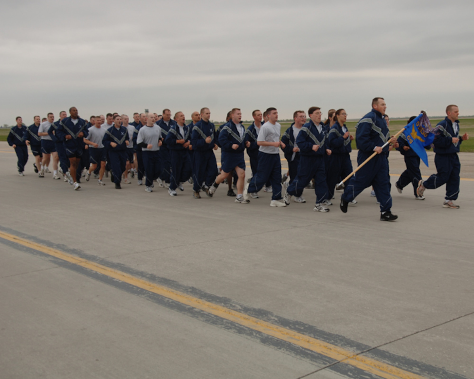 MINOT AIR FORCE BASE, N.D. -- Members of the 5th Communications Squadron run in formation toward the finish line during a 1.5-mile flightline run here May 29. The flightline run is an annual event to promote physical fitness and team building. The 5th CS members were led by their first sergeant, Master Sgt. Kevin Denny, who carried the squardron's guidon. (U.S. Air Force photo by Airman 1st Class Sharida Bishop).