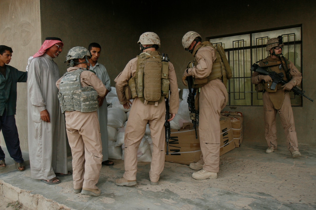 Weapons Company, 3rd Battalion, 6th Marine Regiment, Regimental Combat Team 1 help al Anbar locals here facilitate a civil operation by assisting food bag distribution in the village of Fuhaylat June 4.