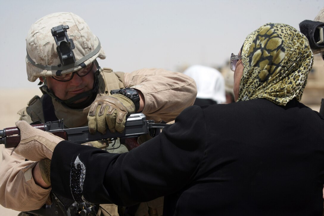 Chief Warrant Officer 3 Charles Major, infantry weapons officer of 3rd Battalion, 6th Marine Regiment, Regimental Combat Team 1 assists a shooter during range training with the Sisters of Ameriyah/Ferris June 4. The program trains women in Iraq to work alongside their male counterparts, the Iraqi Police, at entry control points through Anbar.