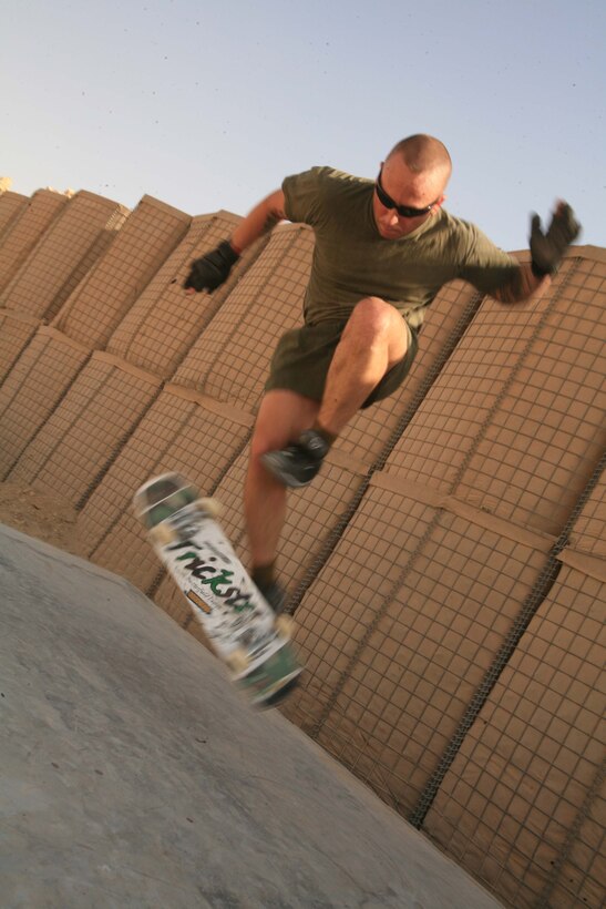 Sporting his green on green physical training gear, freestyle professional skater 1st Sgt. Keith S. Butterfield, first sergeant, Headquarters and Support Company, 7th Engineer Support Battalion, 22nd Naval Construction Regiment, hones his craft behind his office at Camp Taqaddum, Iraq. Butterfield took a break from the skateboarding scene while he started a family and a career in the Marine Corps. After being inspired to bring out his board again, a freestyle skateboarding company has been successfully selling his signature skateboard models that he designed.  (Photo by Cpl. Tyler B. Barstow)