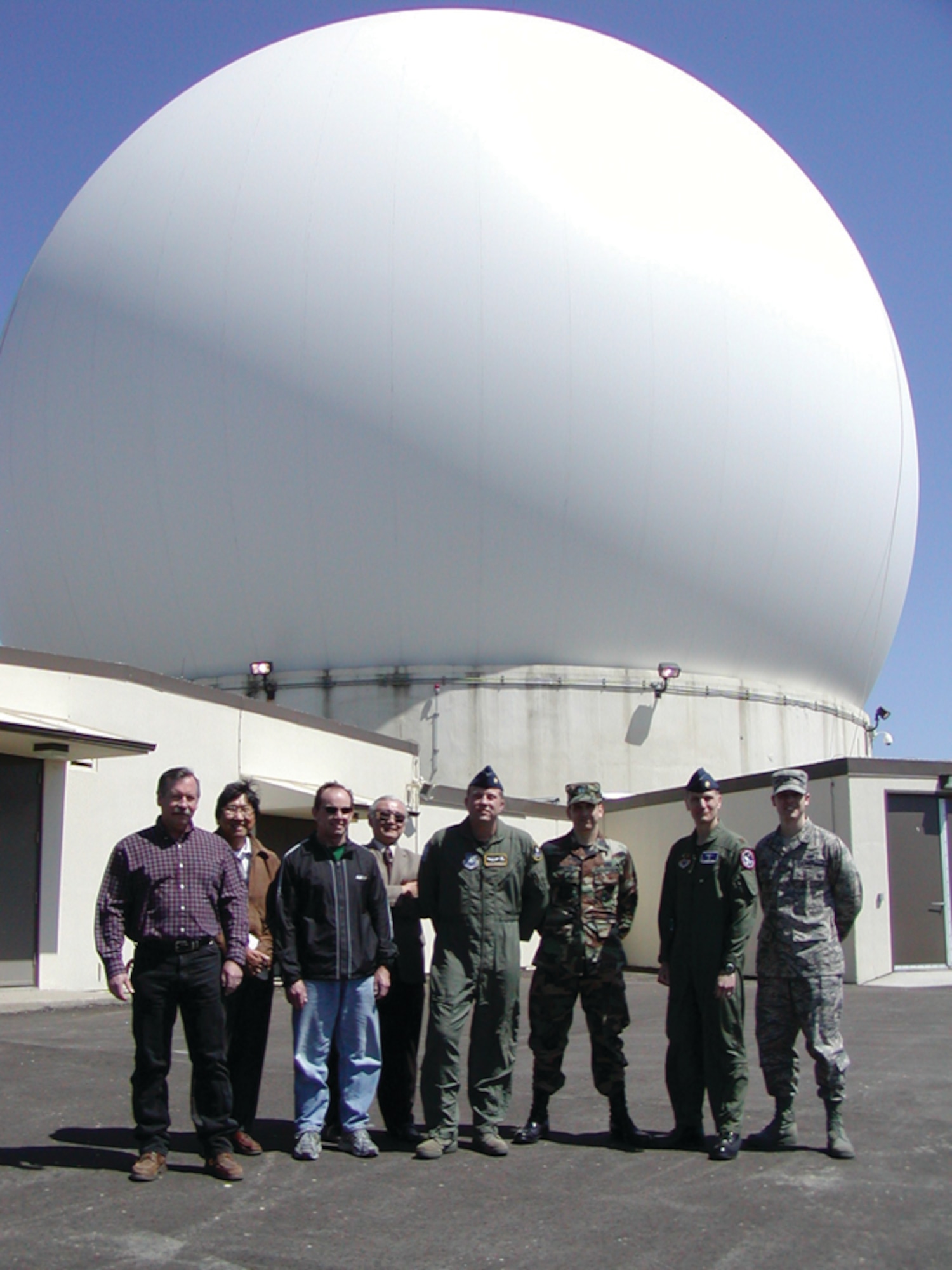 Bruce Collins, Aerospace Corp., Systems Engineer, Roger Abe, HTSI Inc., Site NSI, Dave Foster, HTSI, Engineer, Gil Takahashi, Aerospace Corp., Systems Enginee, Maj Michael Brownworth, 22 SOPS/Det 1 Commander, Capt Lyle Rountree, Deputy Squadron Commander, Satellite Control and Network Systems Group (SCNG), Maj Sean Rucker, Squadron Commander, Satellite Control and Network Systems Group (SCNG), Capt Benjamin Smith, Site Development Project Officer, Satellite Control and Network Systems Group (SCNG) are standing outside the Vandenberg Tracking Station A-Side Antenna (VTS-A)