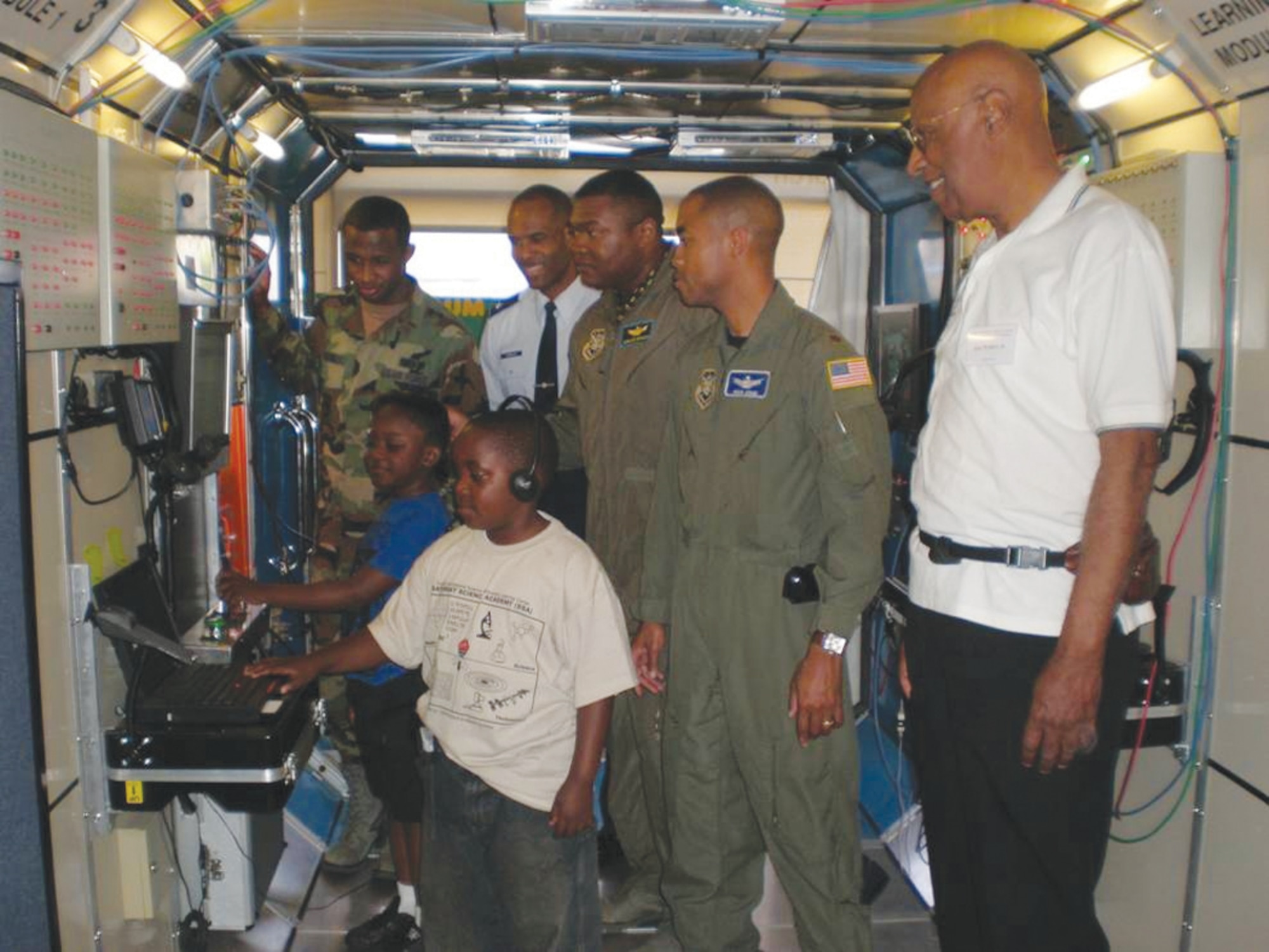 Students get a hands-on technology demo with the assistance of Lt Col Ivan Thompson, Maj Jermaine Brinson, Maj Rico Jones, Lt Rashim McKinney, and Hal Walker Jr., co-founder, African-American Male Achievers Network (A-MAN), Inc. International Science Discovery and Learning Center in Inglewood, California.  (photo by Terita R. Norton, Aerospace Corporation)