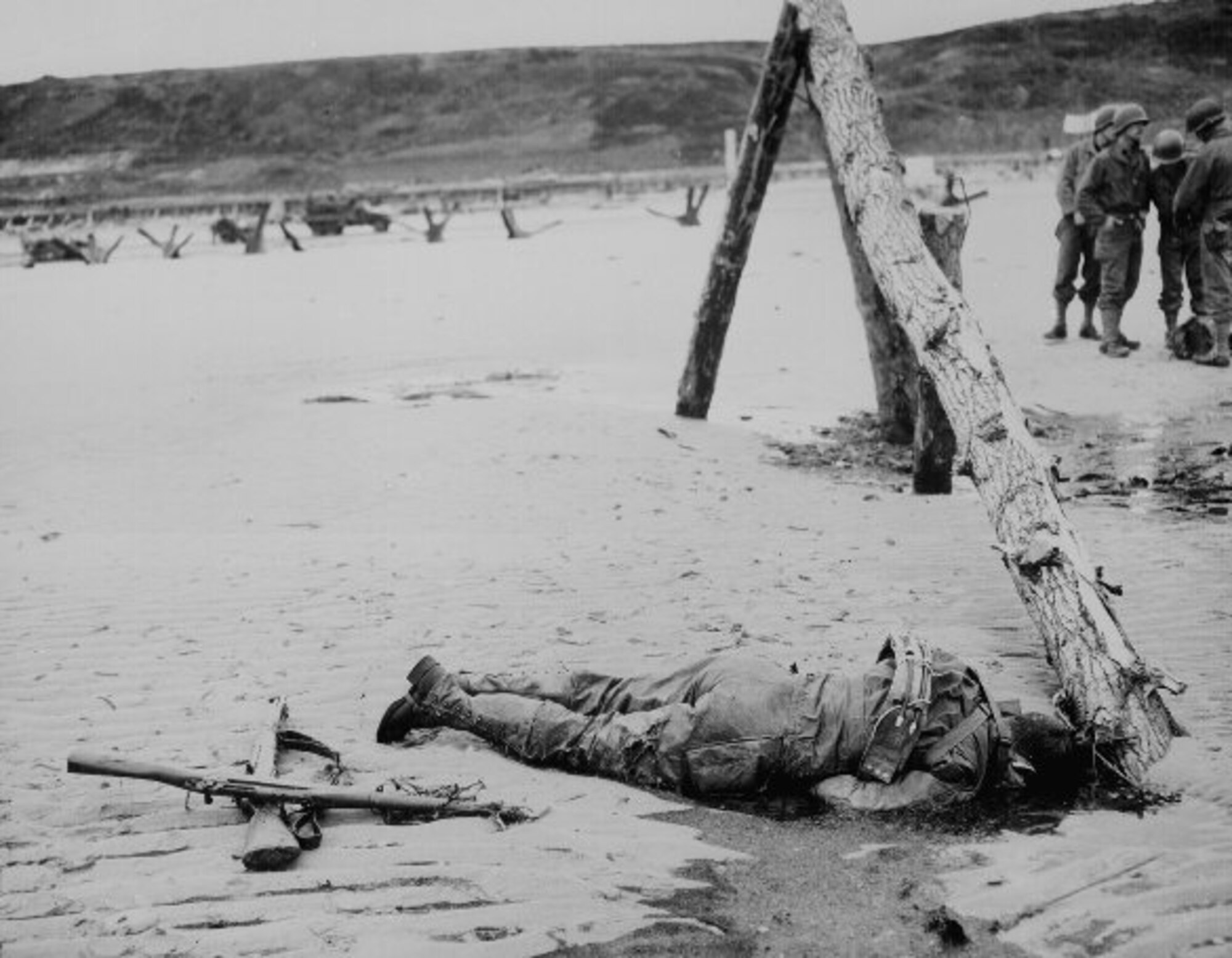 U.S. NATIONAL ARCHIVES -- Crossed rifles in the sand were placed as a tribute to a fallen soldier while allied air forces the sky to attack Germany’s industries and isolate the battlefield. (courtesy photo)