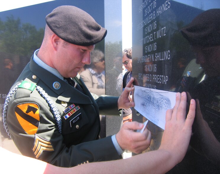 Sgt. Patrick Miller rubs a marking of Sgt. Daniel Morris’ name after the memorial rededication ceremony held at Fort Hood, Texas. (Photo by Whitney Rogers)