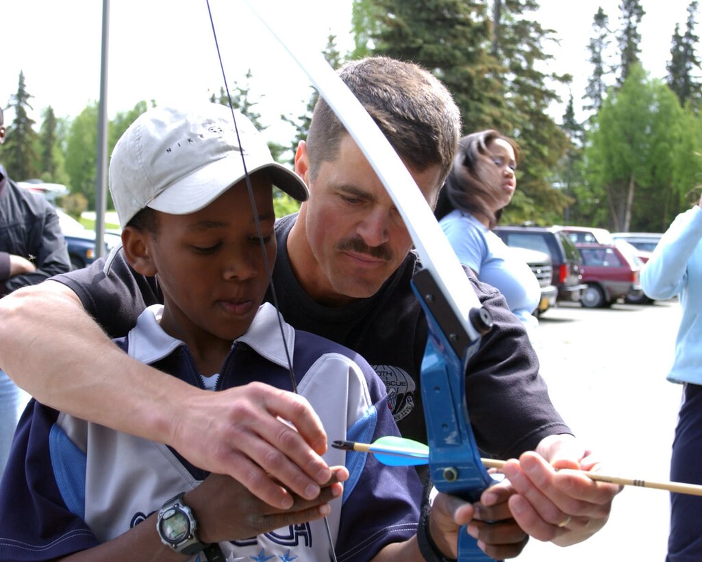 Air National Guard Base, Kulis, Anchorage, Alaska.  The 176th Wing Family day celebration, 02 June 2002.  MSgt Phillip Wilson, from the 210th Rescue Squadron, a family day volunteer, is demonstrating bow and arrow techniques to Marvin Wilson son SSgt Allen Wilson from the 176th Logistics Squadron.  Photo by:  SrA Shannon Oleson