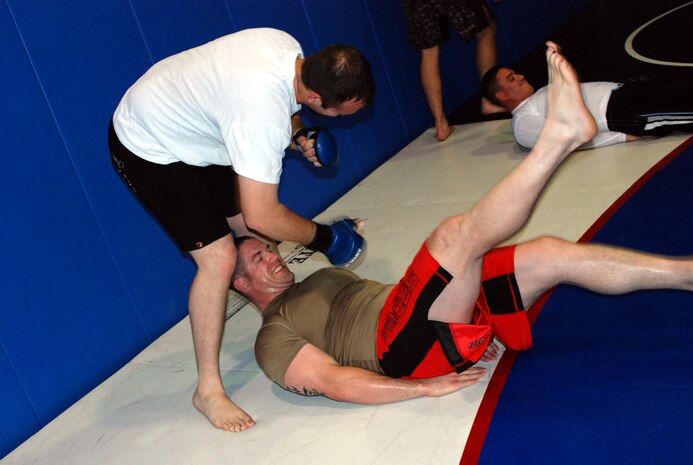 Zach Lefler, standing, helps Tech. Sgt. TJ Wimbs during his abdominal workout at the Omni Fitness Center June 3. The two are part of an informal mixed martial arts training group that meets at 4p.m. Tuesdays and Fridays at the Omni. Sergeant Wimbs took second place at the annual mixed martial arts Pankration Invitational May 17 at Camp Pendelton, Calif. Photo by Staff Sgt. Sarah Gregory