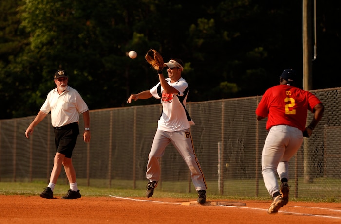 Garrett Forehand reaches to catch a ball while Cornelious Cunningham runs to first base during an intramural softball game at the softball fields on Charleston AFB June 4. With a 21-1 win over the 437th Communications Squadron "Commies," the 437th Aircraft Maintenance Squadron "Inmates" remain undefeated with a record of 8-0.  Forehand plays for the "Inmates" and Cunningham plays for the "Commies."