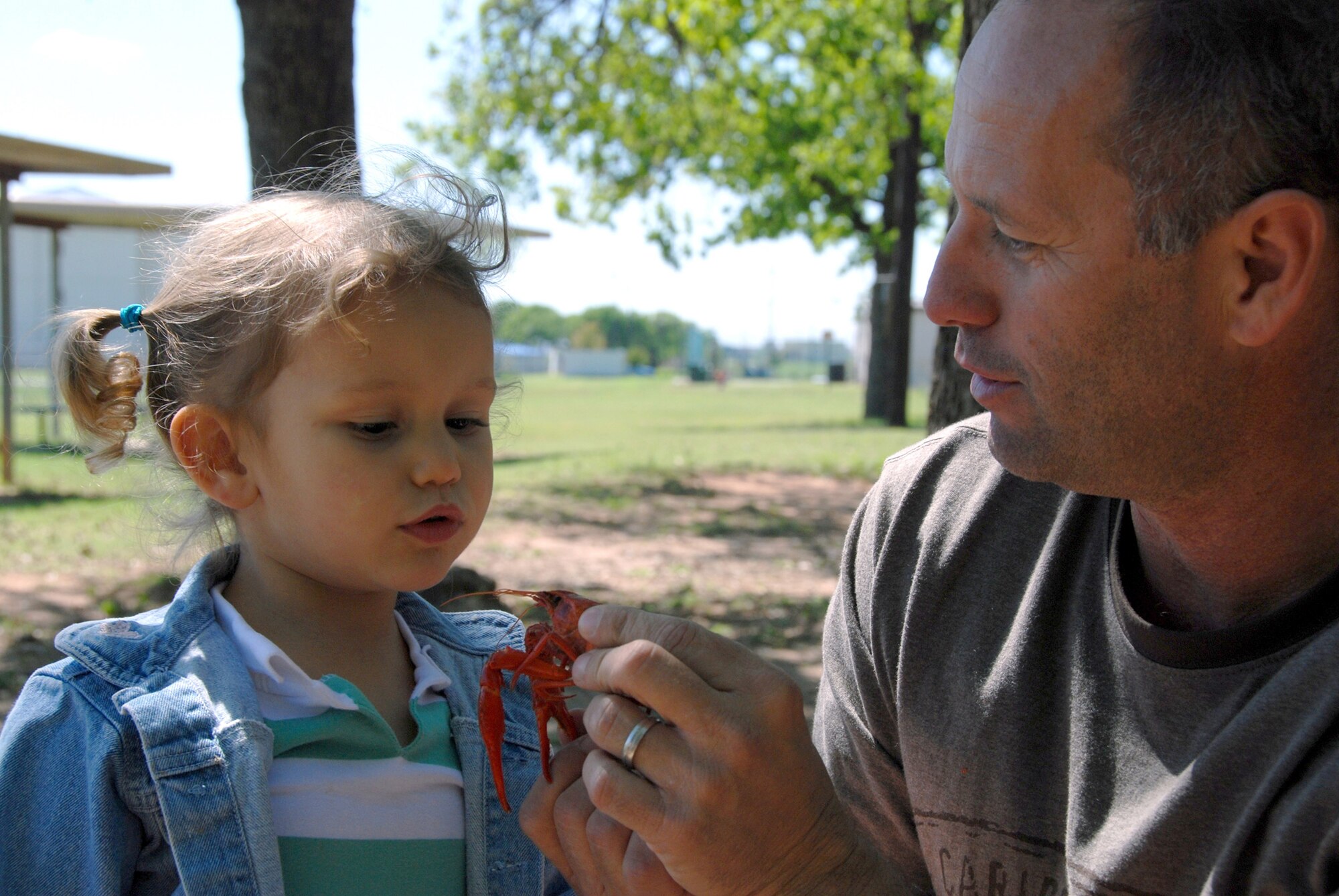 Springtime brings people together at the Naval Air Station Joint Reserve Base Fort Worth, Texas to enjoy a crawdad boil. Jessica, two and a half years old, explores the mystery of a crayfish with her father, Chief Master Sgt. Ricky Hester at a recent outing. The 301st Maintenance Squadron members and their families gathered together recently to enjoy the summertime weather and good friends at the base marina while experiencing a southern seafood delicacy. (U.S. Air Force Photo)