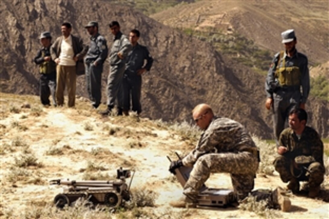 U.S. Air Force Staff Sgt. Jason Snow prepares to send a PACBOT or robot to detect and dispose of bombs to an incident site while local authorities look on in Panjshir, Afghanistan, May 24, 2008. A local farmer contacted authorities when he found two 107mm rockets on a timer aimed at a coalition forward operating base. Snow, a robot operator, is assigned to 755th Air Expeditionary Group.