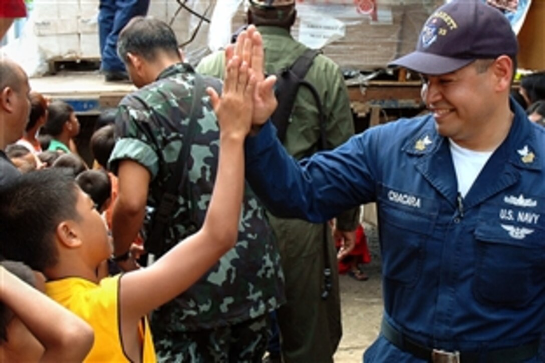 U.S. Navy sailor Carlos Chacara, a personnel specialist, smacks a high-five with a student at West Central Elementary School, the Philippines, June 2, 2008. U.S. maritime and Philippine forces are supporting a variety of humanitarian and at-sea activities during the Philippines phase of Cooperation Afloat Readiness and Training 2008, an annual event between the United States and six Southeast Asia nations to build relationships and enhance the operational readiness of participating forces. 