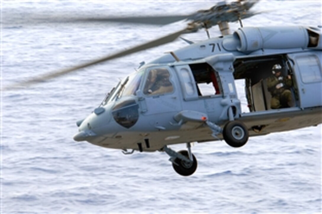 A U.S. Navy sailor peers out of an MH-60S Seahawk after delivering a load of ordnance onto the flight deck of the aircraft carrier USS Ronald Reagan during an ammunition on-load with the Military Sealift Command fast combat support ship USNS Bridge in the Pacific Ocean, June 5, 2008. 