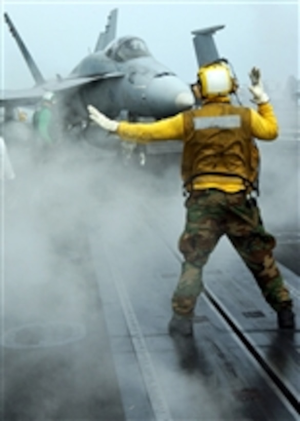 A U.S. Navy aviation boatswain's mate directs an F/A-18 Hornet aircraft into position for launch during flight operations aboard the aircraft carrier Theodore Roosevelt (CVN 71) while at sea in the Atlantic Ocean on April 25, 2008.  