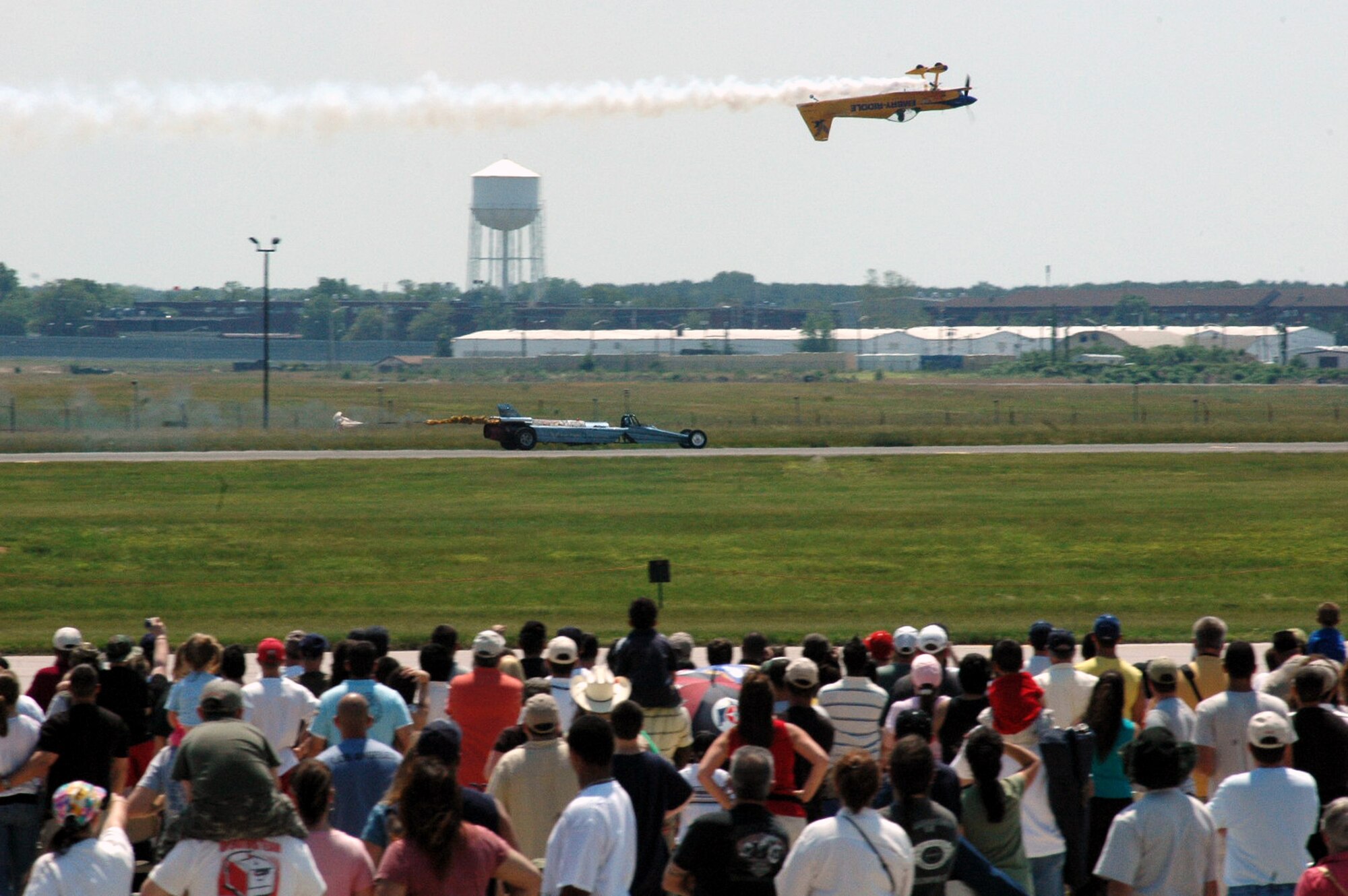 A prop-driven plane flown by the flying team for Embry-Riddle Aeronautical University flies upside-down over the airfield while the Air Force Reserve drag racing car flies down the runway at McGuire Air Force Base, N.J., during the McGuire Air Expo 2008 June 1.  More than 170,000 people attended the Air Expo.  (U.S. Air Force Photo/Tech. Sgt. Scott T. Sturkol)