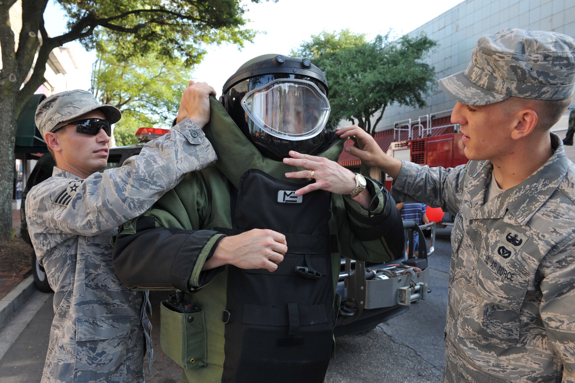 SUMTER, S.C. -- Staff Sgt. Roger Hughes and Airman 1st Class Joshua Labott, demonstrate the donning of an EOD-9 bomb suit on Tech. Sgt. Michael Newbern at the 7th annual Sumter-Shaw Street Fest in downtown Sumter May 30. The Airmen are Explosive Ordnance Disposal team members from the 20th Civil Engineer Squadron. The festival gives Shaw members the opportunity to interact with the local community and educate them about Shaw's mission. (U.S. Air Force photo/Tech. Sgt. Josef Cole III)